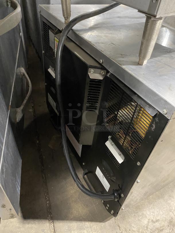 Amana commercial stainless steel microwave oven, 208-230V, shown from the back with visible power cord and vent.