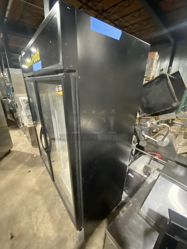 True commercial black double glass swing door reach-in merchandiser freezer, Model GDM-49F-HCX-TSLO1, with poly-coated wired rack.