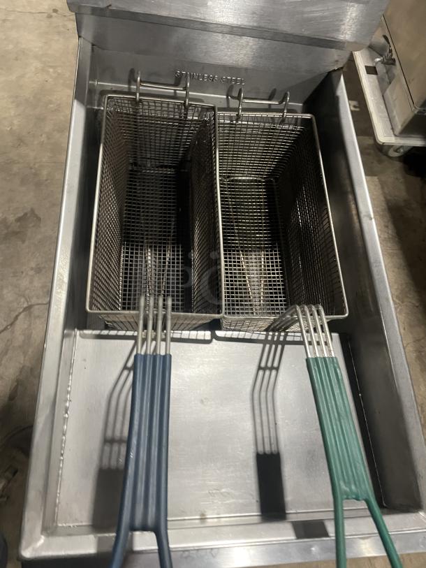 Imperial stainless steel deep fat fryer with baskets, back splash, and basket hanger. Natural gas powered, on legs, marked "Stainless Steel."