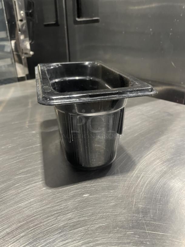 Commercial black plastic food pan in good condition with a rectangular opening, placed on a metal surface.
