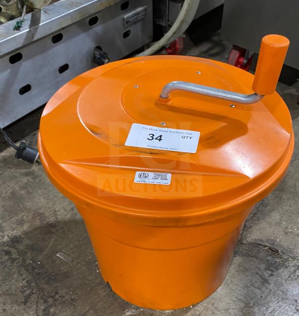Orange commercial salad spinner with handle, labeled "34" for auction. Features ETL certification marking. Durable condition.
