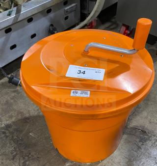 Orange commercial salad spinner with handle, labeled "34" for auction. Features ETL certification marking. Durable condition.