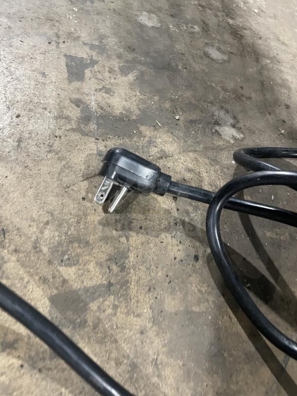 Plug of a Glastender F1SB24 cooler/refrigerator, shown on a concrete floor. 120V, 1 Phase, 60HZ power specification.