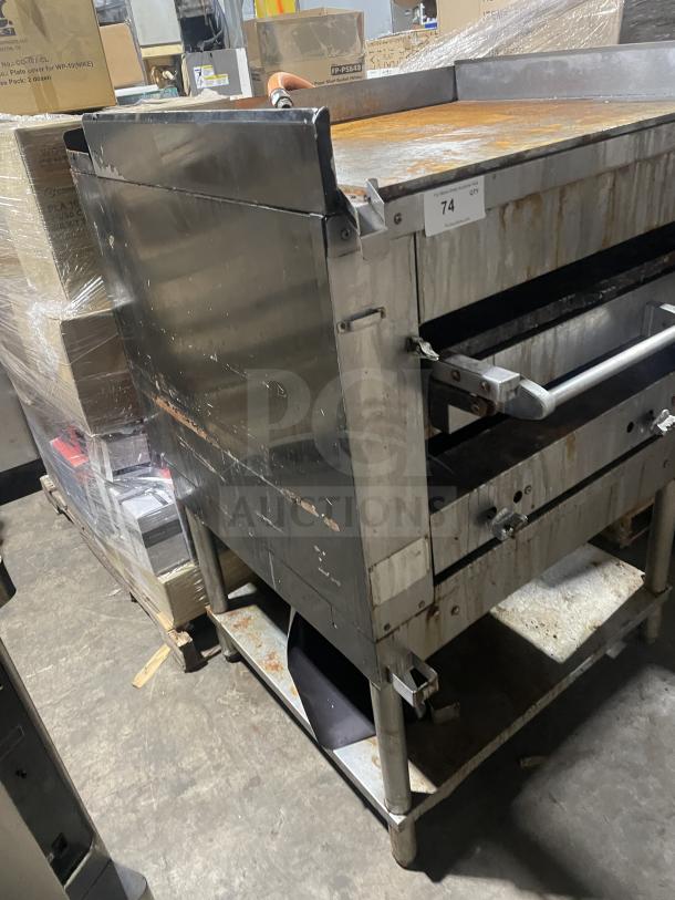 Montague stainless steel gas char broiler grill, Model C36SHB, on legs with storage. Visible wear, mounted on casters.