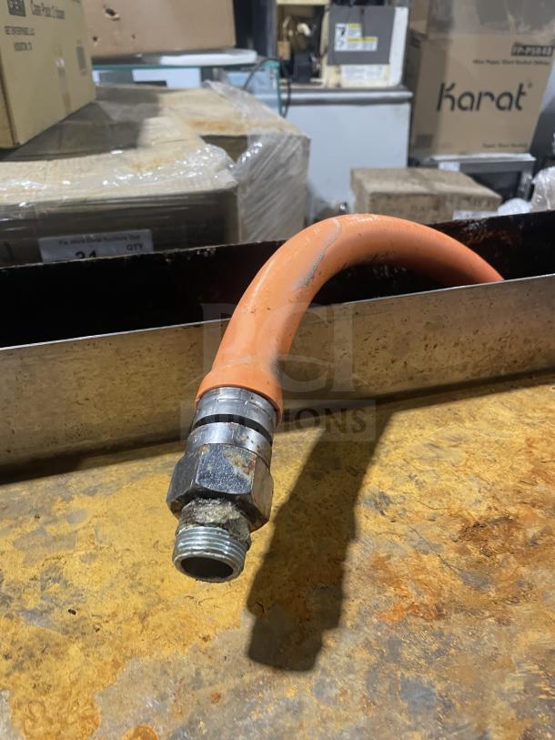 Orange gas hose attachment on a stainless steel surface, part of Montague gas char broiler grill model C36SHB.