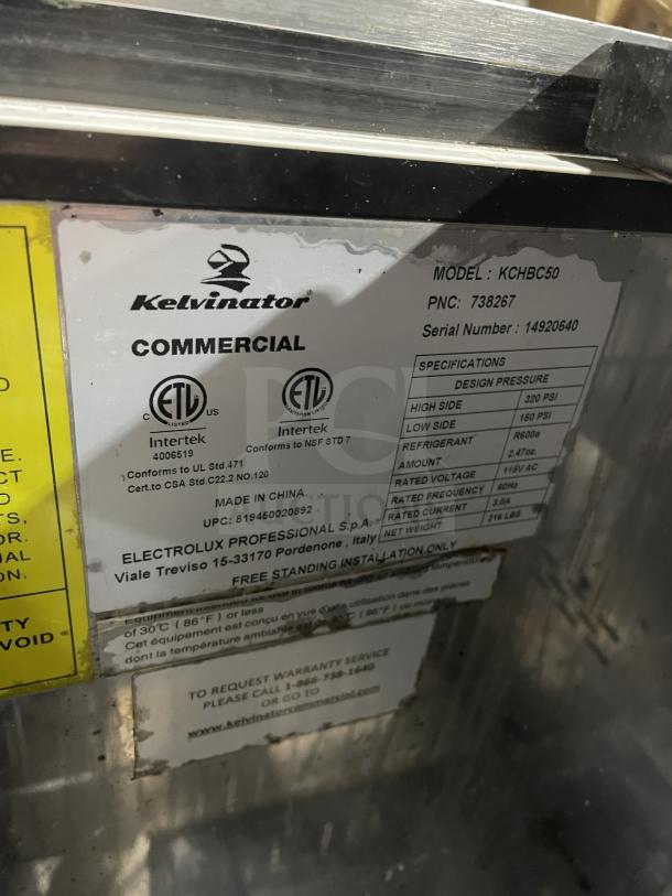 Kelvinator Commercial Bottle Cooler, Model AUB50RZ, stainless steel, top lids, on casters, 115V, 60HZ. Labels indicate specifications.