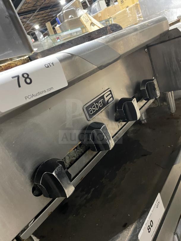 Asber commercial stainless steel countertop gas griddle with side splashes and legs, visible control knobs, and condition signs.
