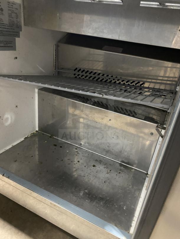 Kelvinator KCHST278 salad/sandwich prep table, stainless steel, single door, with wired rack, on casters, interior view.