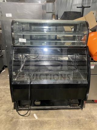 Black dual service refrigerated display case merchandiser in good condition. Features curved glass front and two shelves.