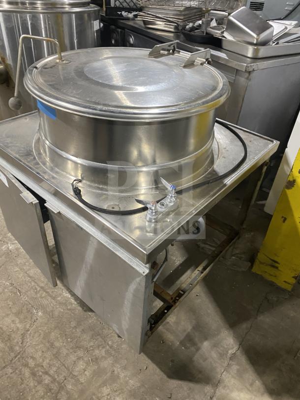 Commercial stainless steel steam kettle with power tilt, on legs. Used condition, sturdy build, suitable for high-volume cooking.