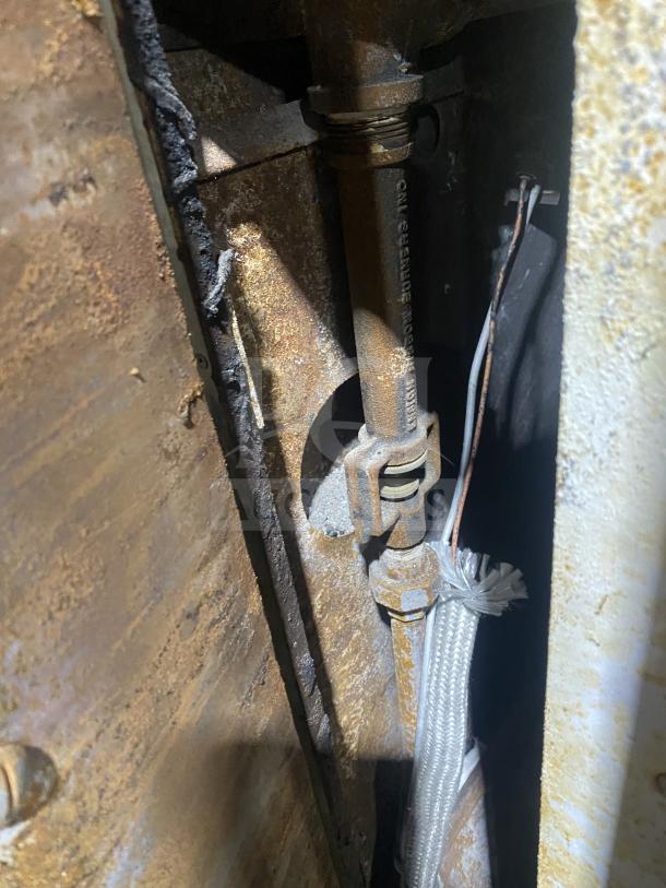 Interior view of Bari Model 648 gas-powered pizza oven showing metal piping and wiring, indicating wear and rust.