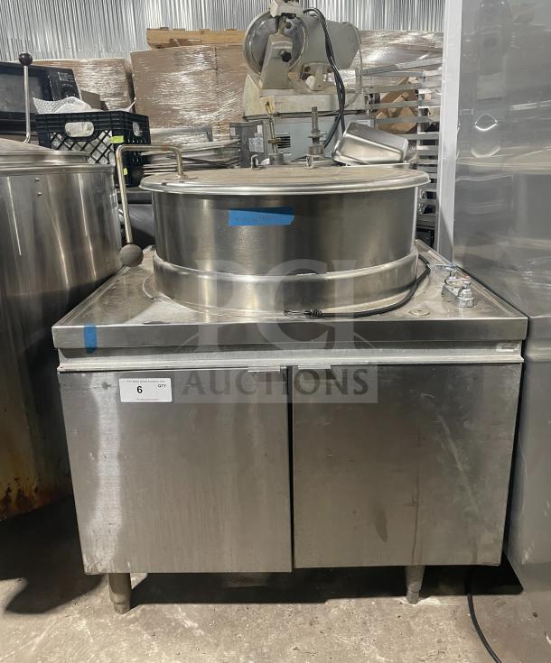 Stainless steel steam kettle with power tilt on sturdy legs, commercial-grade construction, moderate wear, labeled "6 Qty."