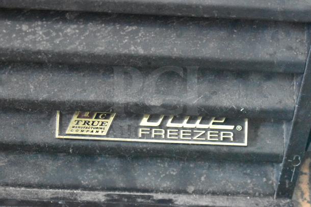 True GDM-72F-LD Commercial Freezer label, indicating model and make. Black surface with visible dust.