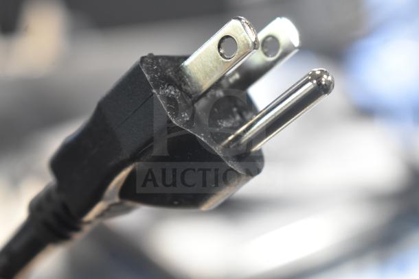 Close-up of a power plug for a Vita-Mix VM0101 blender, visible metal prongs and black plastic casing.