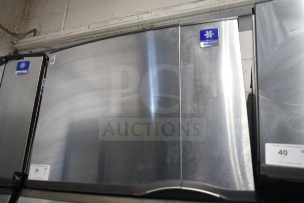 Manitowoc commercial ice machine head on hotel dispenser, stainless steel finish, 115 volts, 1 phase, branded label visible.