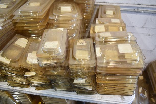 Tabletop lot of amber-colored drop-in bin lids, including FG202P22AMBR and FG221P86AMBR models. Stack of lids.