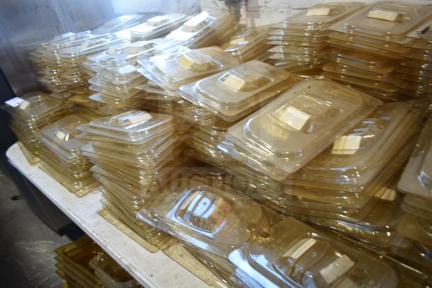 Stacks of amber-colored drop-in bin lids, models FG202P22AMBR and FG221P86AMBR, in new condition on a tabletop.