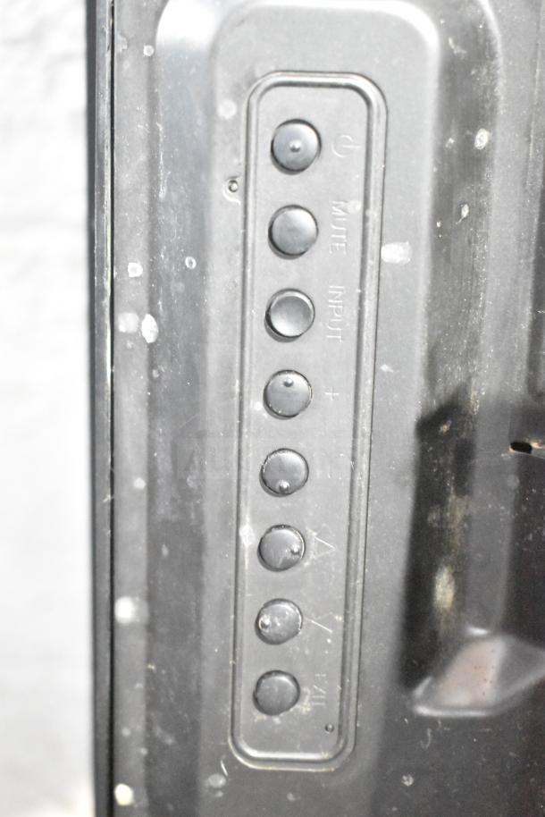 Close-up of NEC V463 television controls, showing buttons for power, mute, input, and volume. Minimal wear visible.