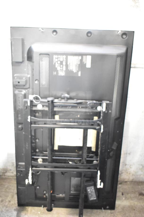 Back view of NEC V463 television, mounted on a black stand, showing ports and venting. Buyer pick-up required.