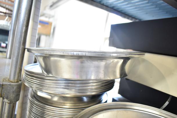 Forty metal dome covers stacked, shiny finish, good condition. Offered at auction, 40 times bid value.