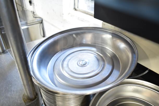 Stack of shiny metal dome covers in good condition, with a smooth, reflective finish. Auction lot of 40 covers.