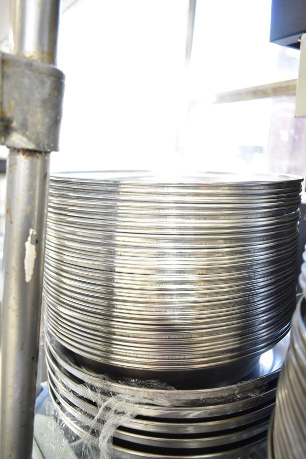 Stack of 40 metal dome covers, shiny finish, suitable for various uses. Good condition, available in bulk lot auction.