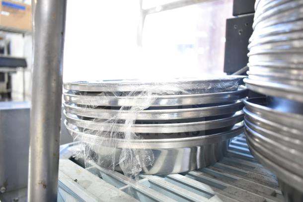 Alt text: Stack of 40 metal dome covers, wrapped in plastic, shiny and well-maintained, ideal for catering use.