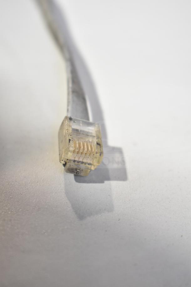 Close-up of a yellowed RJ11 phone cable plug on a white surface.