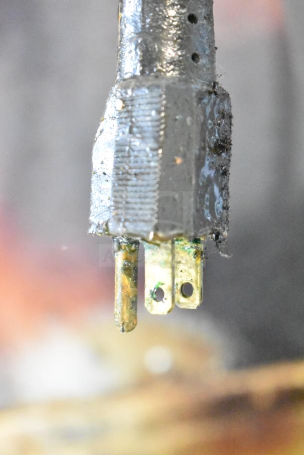 Close-up of a corroded metal plug with visible grime and discoloration. It appears worn and used.
