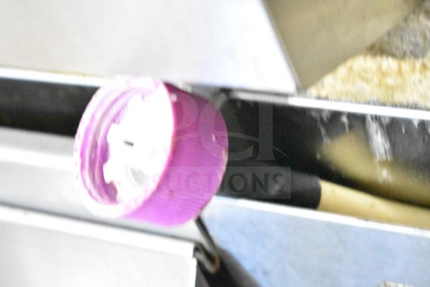 Alt text: Blurry close-up of a purple plastic knob on metallic machinery.