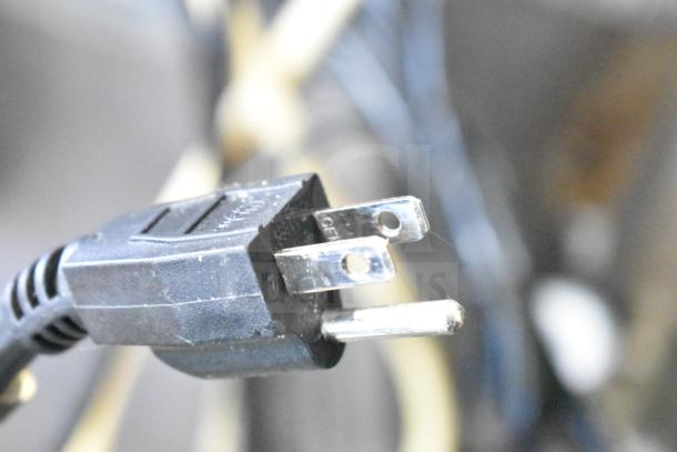 Alt text: Close-up of a three-prong electrical plug with visible metal prongs and a black plastic casing.