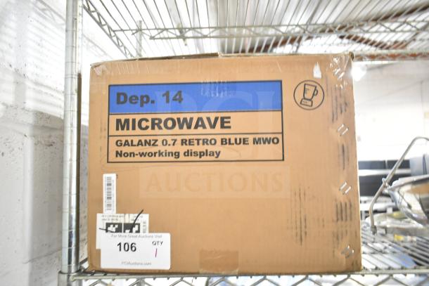 Cardboard box labeled "Galanz 0.7 Retro Blue MWO" on shelf, indicating a non-working display microwave.