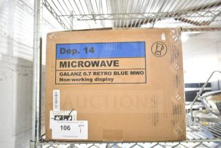 Cardboard box labeled "Galanz 0.7 Retro Blue MWO" on shelf, indicating a non-working display microwave.