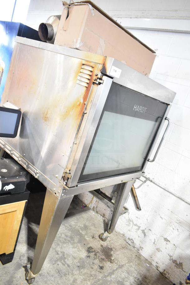 Hardt Inferno 4500 stainless steel commercial rotisserie oven, natural gas powered, with skewers, metal legs, and casters.