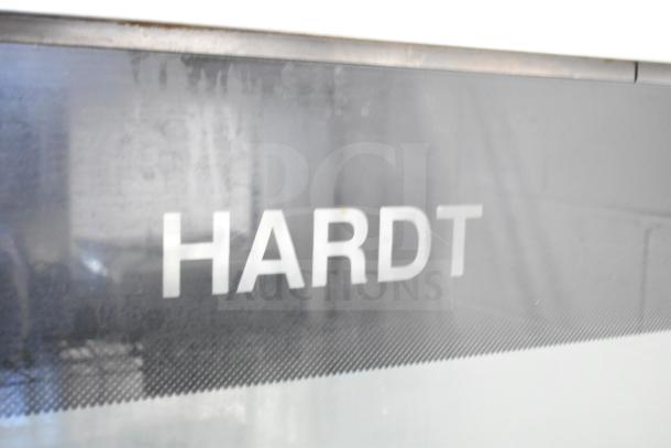 Hardt Inferno 4500 stainless steel commercial gas rotisserie oven, includes skewers, on metal legs with casters.