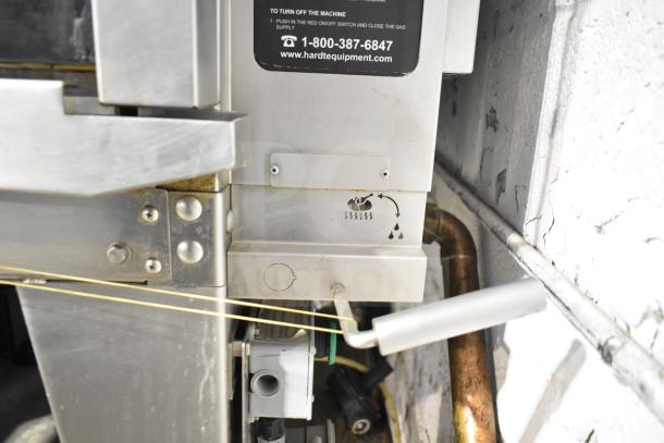 Hardt Inferno 4500 stainless steel commercial rotisserie oven, natural gas powered, with skewers, metal legs, and commercial casters.