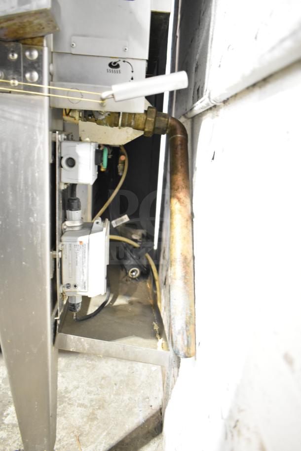 Hardt Inferno 4500 stainless steel commercial rotisserie oven, natural gas-powered, with skewers and metal legs on casters.