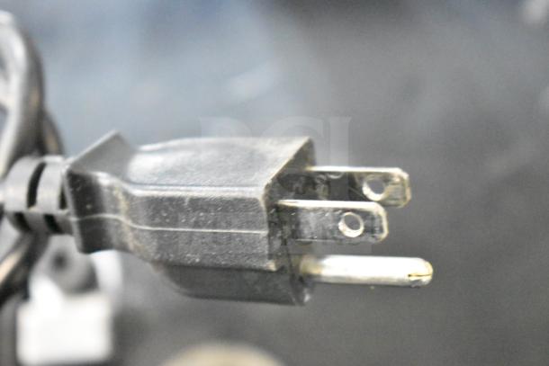 Close-up of a power plug for a 2023 Hobart HTi-SSLSC commercial food portioning scale. Plug is a standard three-prong type.