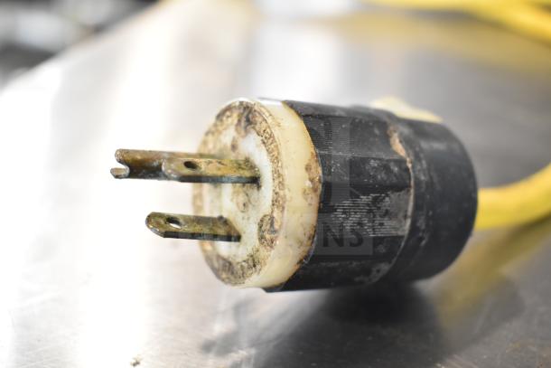 Close-up of a worn electrical plug attached to a yellow cord, possibly from a Cleveland 24CGA6.2S steam cabinet.