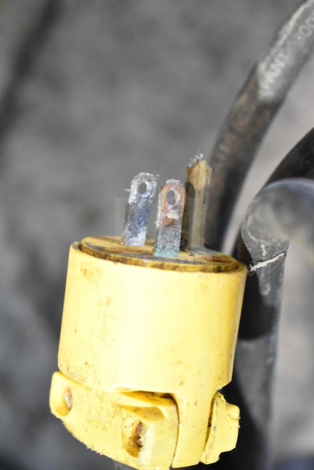 Unic Phoenix espresso machine plug detail; yellow casing, three metal prongs, attached to a black cable.