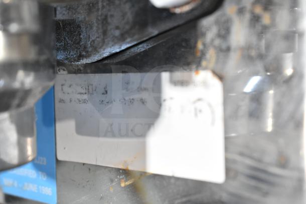 Unic Phoenix espresso machine model tag, showing voltage and phase details. Slight wear visible on surrounding metal.