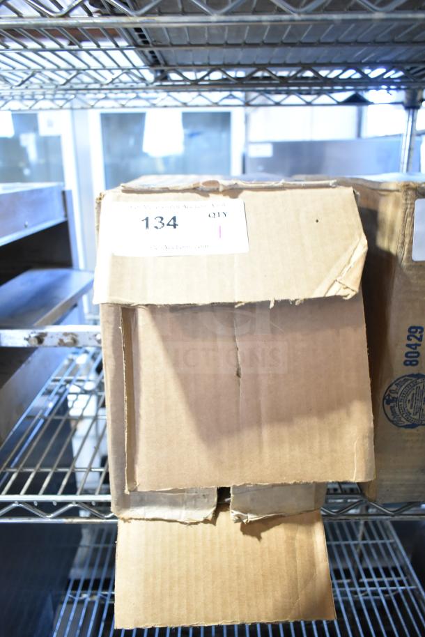 Cardboard box labeled "134" on shelving, containing Baxter Mini-K Compressor, 115 Volts, 1 Phase. Box is slightly worn.