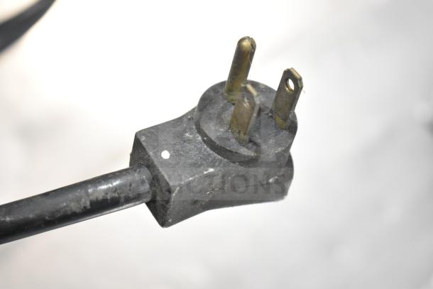 Close-up of a three-pronged electrical plug attached to the Multiplex MA-8-1US Commercial Blend In Cup Workstation.