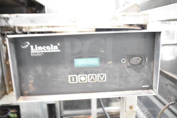 Lincoln Impinger commercial conveyor pizza oven on equipment stand, with control panel. Visible wear indicates used condition.