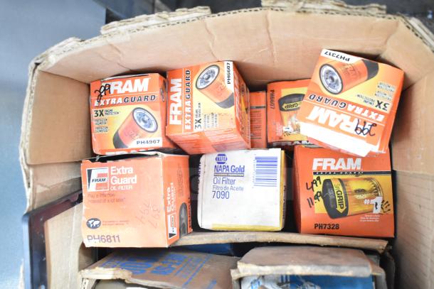 Lot of automotive parts including Fram PH4967 Extra Guard oil filters and Napa Gold 7090 oil filter. Various items in packaging.