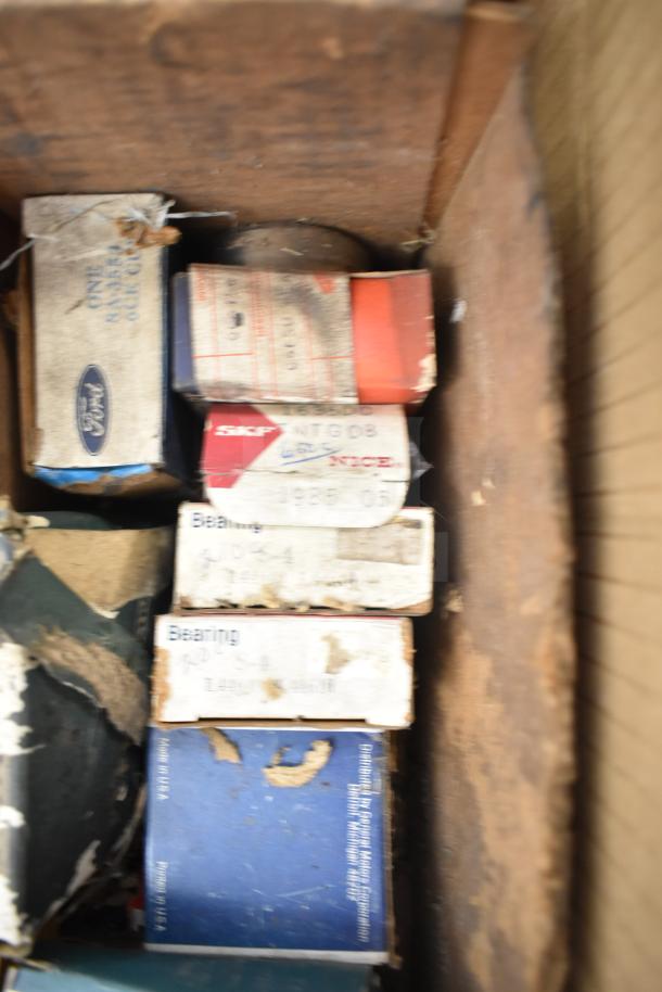 Box of various automotive parts including Fram PH4967 Extra Guard, worn packaging, includes Napa thermostat and bearings.