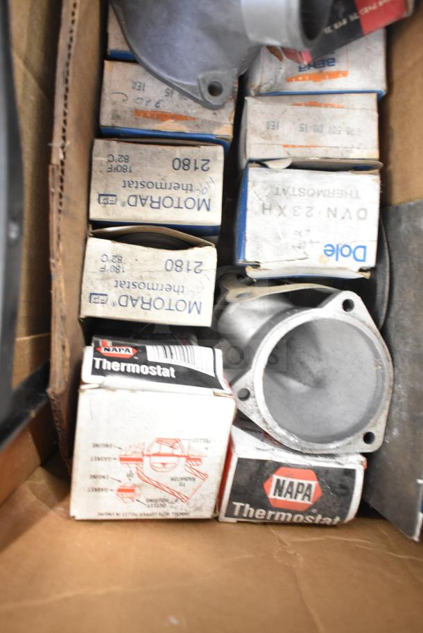Lot of automotive parts including Fram PH4967 Extra Guard filter, Napa and Motorad thermostats in original packaging.
