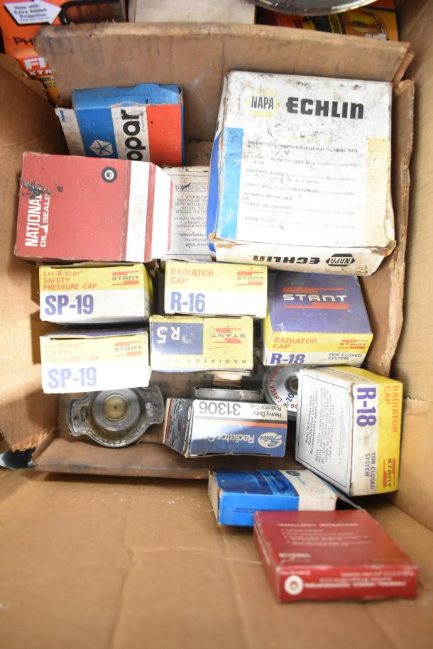 Lot of automotive parts, including Fram PH4967 Extra Guard, Napa thermostat, various radiator caps. Mixed condition.