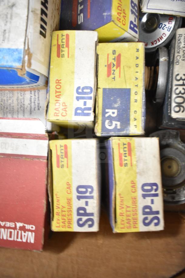 Lot of automotive parts including Stant radiator caps R-16, R5, SP-19, Fram PH4967, and Napa thermostat in original boxes.