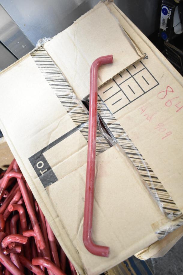Lot of 4 boxes with red metal pieces, possibly hardware tools, in used condition. Cardboard box has visible handwritten numbers.